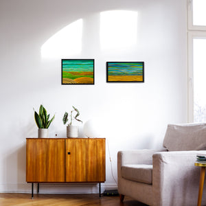 Two small framed prints on a wall showing an ocean and hills. Colours are blues and yellow earth tones