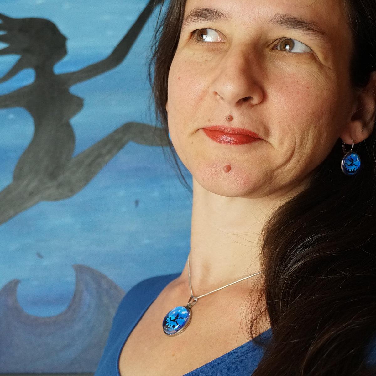 I am Free! Necklaces featuring a vibrant blue medallion with night sky and leaping figure design.