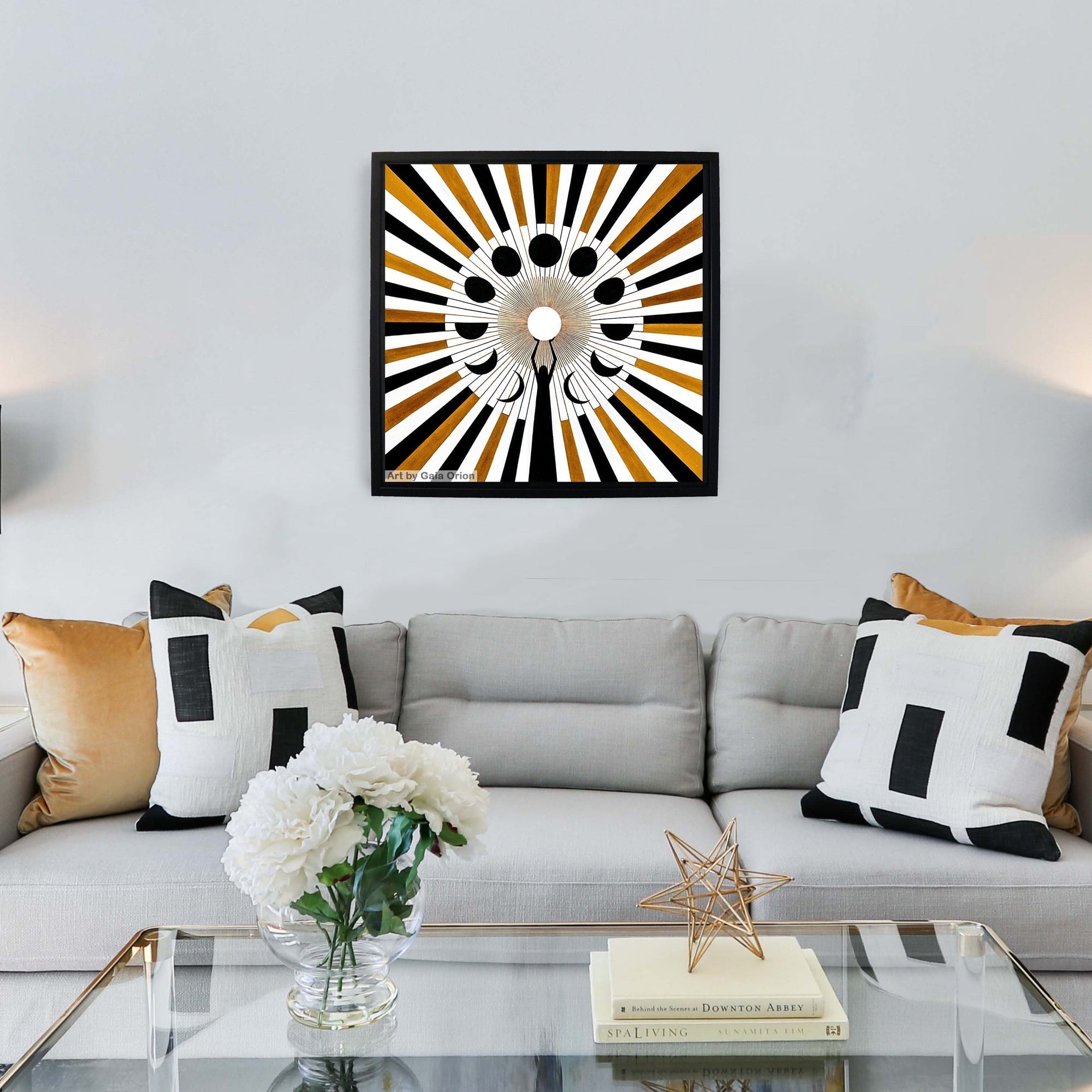 A framed print on canvas above a couch about sacred feminine moon cycles black and white and gold mandala